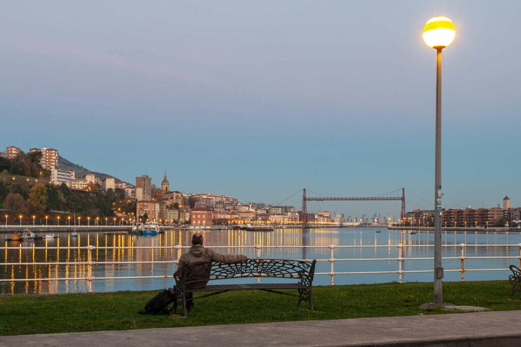 Un hombre sentado en un banco admirando el puente Vizcaya en Bilbao