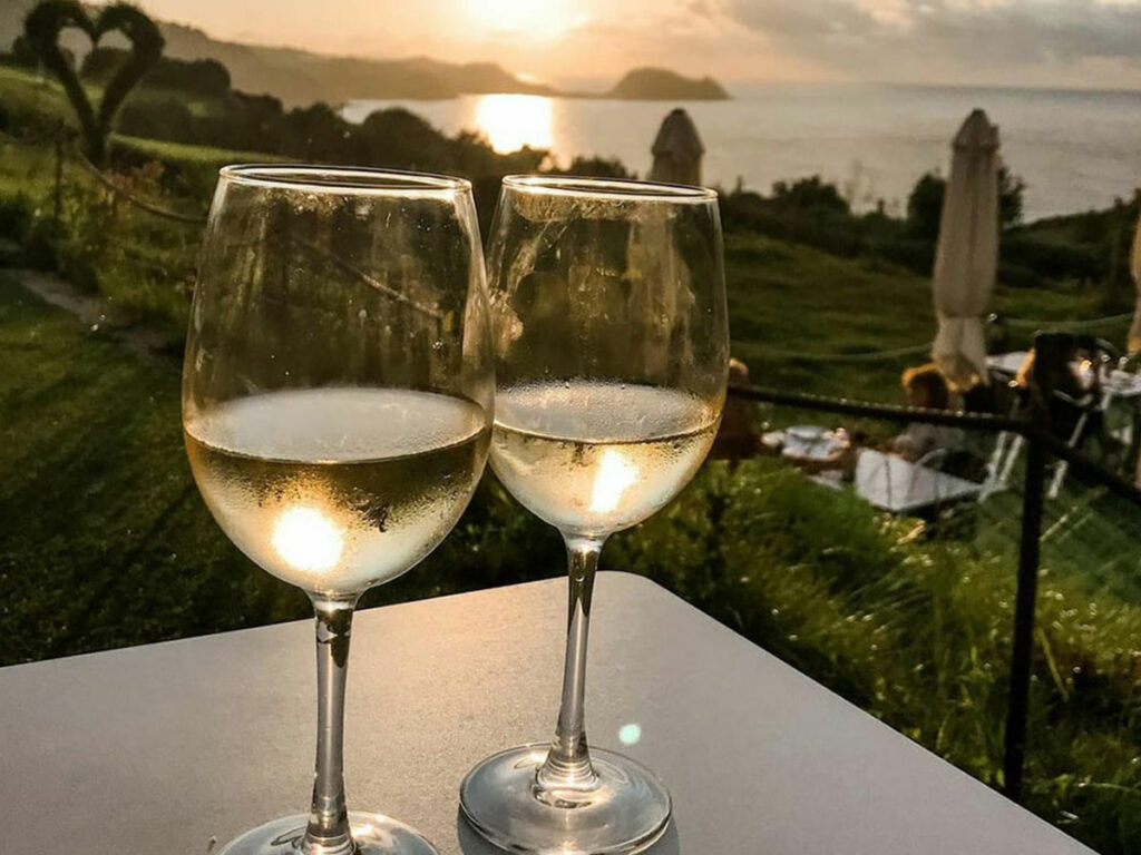 copas de vino txakoli con el mar de fondo y puesta de sol