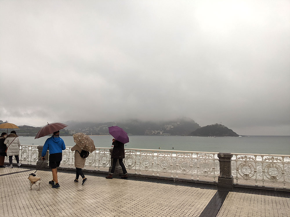 People walking on paseo de la concha in the rain