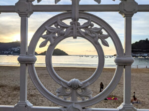 View through the holes of the white railings railing on la concha beach